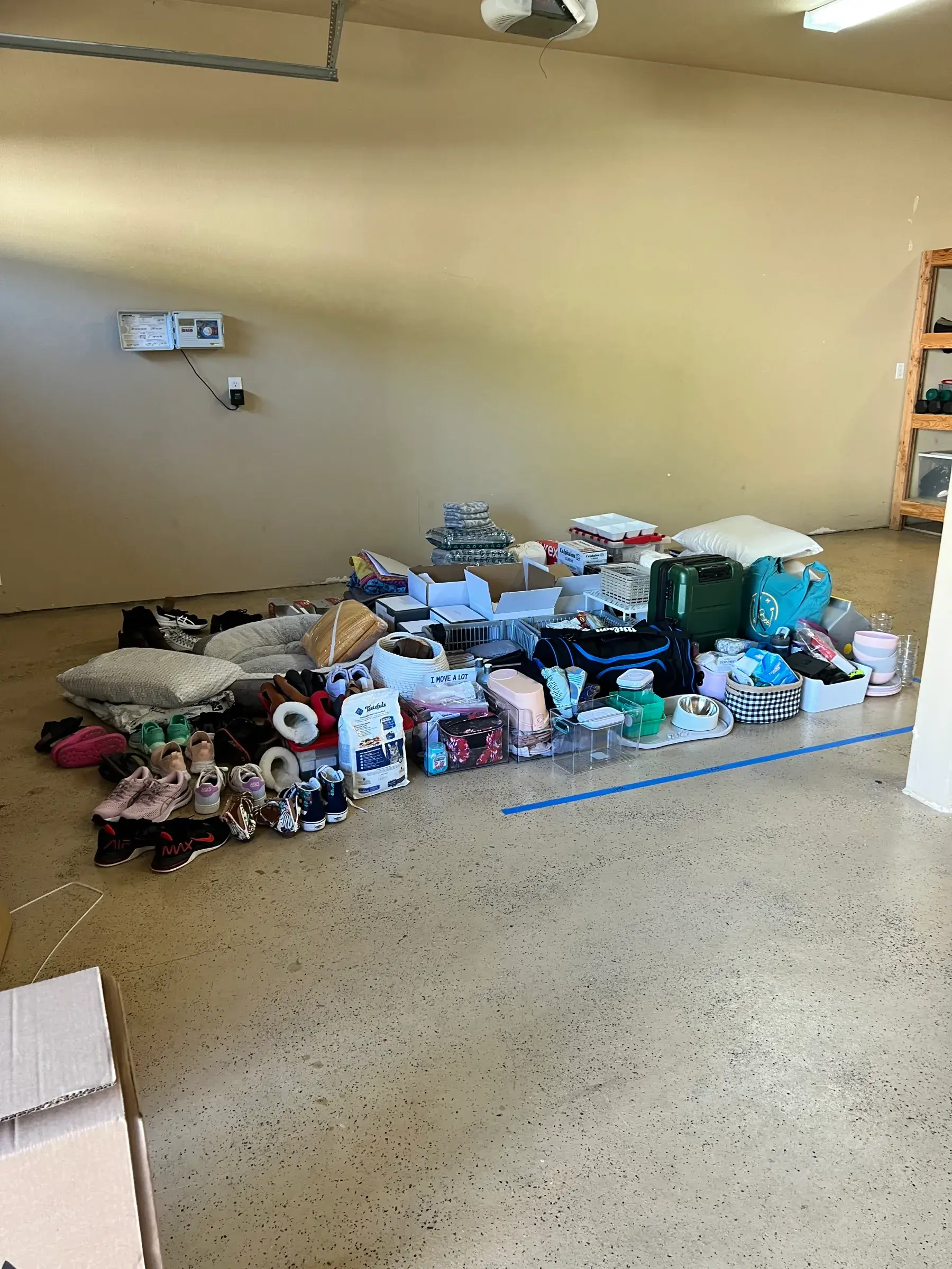 Household items, shoes, pillows, and storage bins are neatly arranged in a garage before being packed or donated during an international move. Organizing only the essentials reflects the minimalist lifestyle that comes with living overseas.